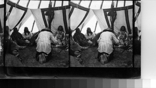 Shows central figure imitating the pose of a bear, and approaching on his knees [to] the wife of the Medicine Man. Fort Belknap Reservation, Mont., July 1906