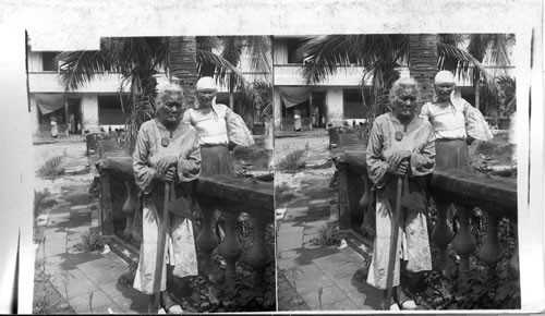 A Filipino grandmother of the poorer class enjoying a cigar, Cavite, P.I