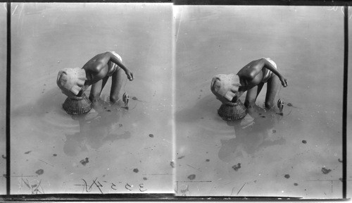 A Filipino boy fishing. (The basket serves as sort of trap to catch certain kinds of mud fish in shallow water). Philippines