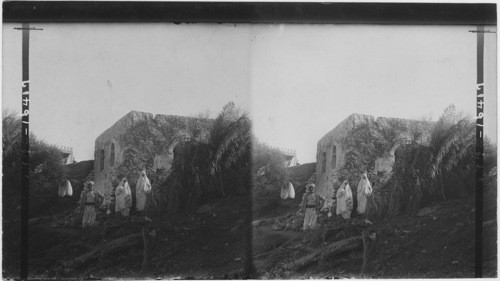 An Arab and his veiled women outside their home, Algeria