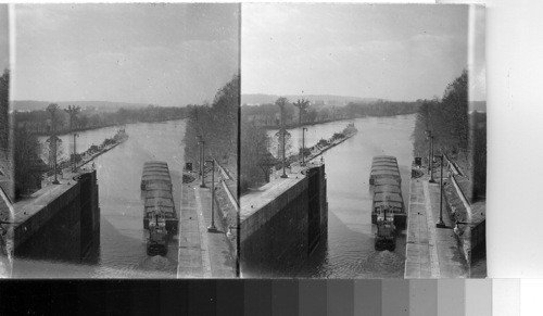 Boat and oil barges leaving the lock going down the river with boat and barges of oil waiting to enter the lock