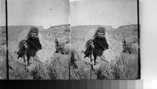 Masked Indian sitting on rocks. Arizona