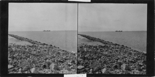 A ship laying at anchor just off the east end of Galveston Island. The ship of land seen to your right is Bolivar Point. The rock at your feet is the jetties that run to the lighthouse to your back