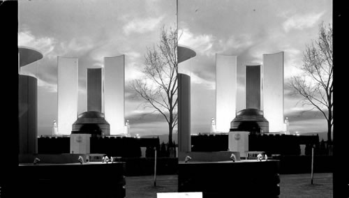 Guarding the entrance to the Court of States, The Federal building's towers loom high into the evening sky. The lights have just flashed on--the color of the sunset is still lingering in the sweep of clouds beyond