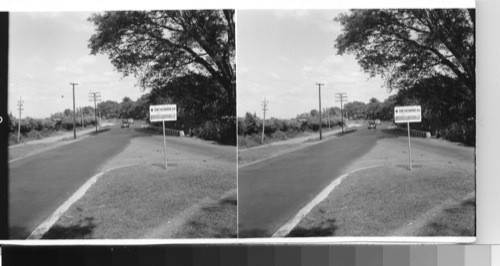 The Pan-American Highway, east of the capital [capitol] city, on the way in from Guatemala. Here as in many places along the highway as it approaches busy cities, but is still bordered by farms or plantations, a dirt road will run parallel to the paved road. this gives automotive traffic more freedom to travel faster than it could if the road were constantly used by horse or oxen drawn carts, etc. near Santa tecla [Nueva San Salvador], el Salvador, C. A