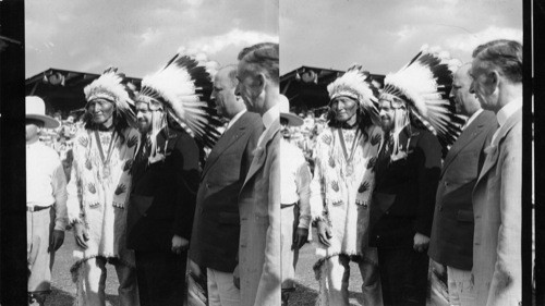 Chief Blackhorn of Sioux Tribe as he put helmet of feathers on Balbo, Italian Flier, Name given Balbo was "Flying Eagle"
