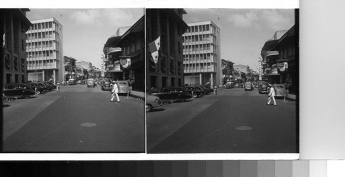 Avenida Central, the principal thoroughfare of Panama city, has taken on a very modern with its fine new buildings which are neighboring or replacing the older business buildings of the city. This is about the busiest corner of its whole winding length. Panama City, Republic of Panama, C.A