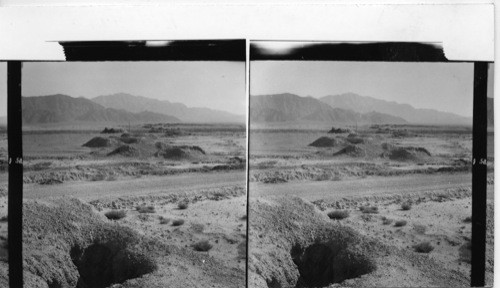 152 Row of ganat mounds. Somewhere in the hills in the distance the water has originally been found. It is led to a village about 8 miles distance from the spring. The artificially made under-ground streambed is not lined with timber or planks. It is just cut through the earth. It happens that the soil sometimes caves in and blocks the waterflow. Through the vertical shafts the earth is being hoisted up in buckets, when cave-ins occur