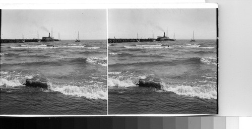 The harbor of Granada on Lake Nicaragua, showing the pier jutting out into the waters of this lake which is the largest between our own Great Lakes and Lake Titicaca of Bolivia, S. A. A banana boat from Ometepe island in the lake is bobbing about offshore while small rowboats and sail boats unload her cargo. A larger lake boat is tied up while her cargo is discharged at the pier. Granada, Nicaragua, C.A