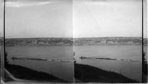 Tug pulling twelve scows loaded with coal from U.S. Two scows lashed together side by side. Canada