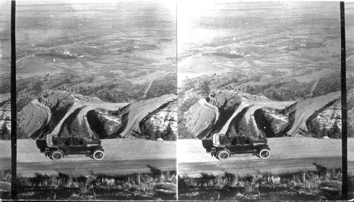 On the Broadmoor. Cheyenne Mountain Highway from "Rampart Swing", (elevation 7900 ft.) N.E. to Spiral Shelves. In the distance below we see the Broadmoor Hotel & Colorado Springs