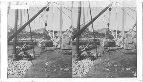 Granite Belguine block paving stones being placed on sailing ship for transportation. Boston, Mass