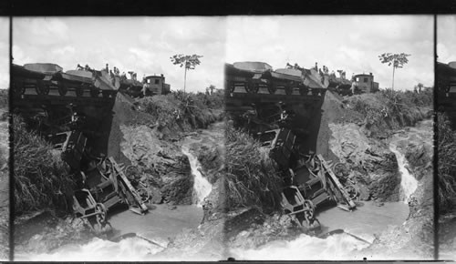 A dumping train unloading soil over old French cars to repair a break on the Panama Railroad. Panama