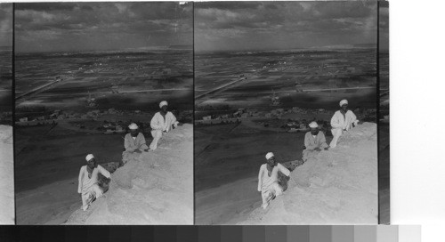 From the summit of Cheops. The guides are just completing the ten - minute climb. beyond- a little north of east, is the city of Cairo. Gizeh, Egypt