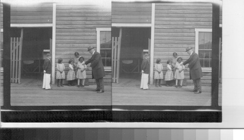 Geo. Buchanan handing pennies to Indian children. Canada