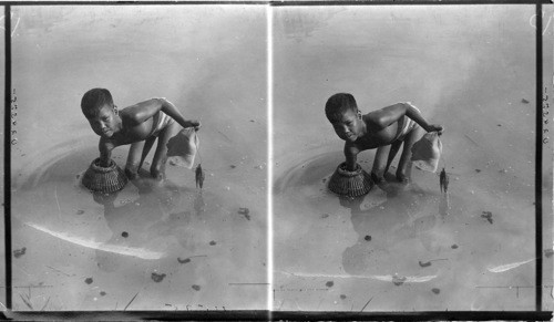 A Filipino boy fishing. The basket serves as sort of trap to catch certain kinds of mud fish in shallow water. Philippines