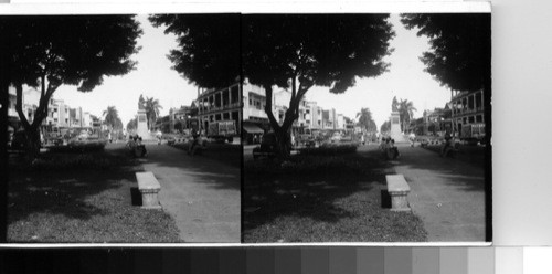 The downtown end of the Avenida Central whose park-like promenade is bordered by homes, schools, motion-picture houses, churches, hospital, public market, and many small merchants. The monuments to the heros of the great fire which destroyed most of the downtown section of Colon stands in the center of the Avenida. Colon, Republic of Panama, C.A