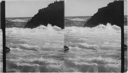 Looking up the Gorge of Niagara, showing the Upper Arch Bridge and distant Falls. Niagara Falls, N.Y