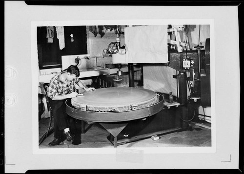 Don Osgood Hendrix examining the Schmidt camera correcting plate, at the Santa Barbara optical shop in Pasadena