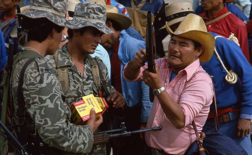 Two soldiers providing shotgun shells for a Mayan civilian, Chajul, 1982