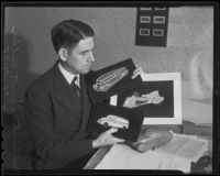 W. E. Miller, automobile designer, holds illustrations of 3 car designs, Los Angeles, 1935