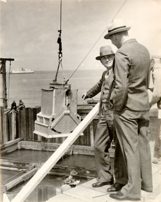 [Two unidentified men standing near the construction site of the San Francisco-Oakland Bay Bridge]