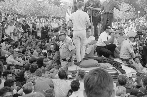 Crowd around and atop the police car in Sproul Plaza holding Jack Weinberg