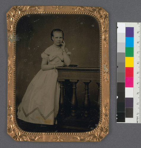 [Full length portrait of Maye C. Bourn, standing, with hand at cheek.]