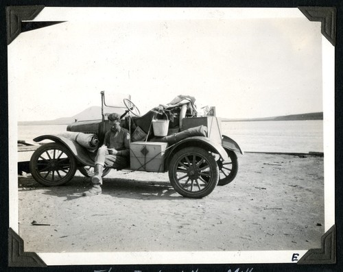 Warren writing in his journal while seated on the running board of the Ford at the abandoned flour mill on San Quintín Bay