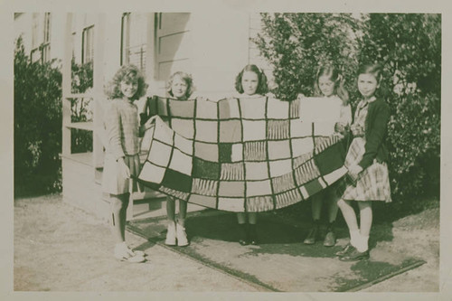 Girls holding a quilt in front of Canyon School in Santa Monica Canyon