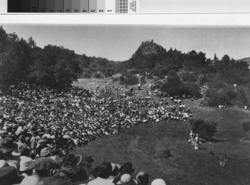 Audience, including crashers atop Pohli Rock, watching early Mountain Play