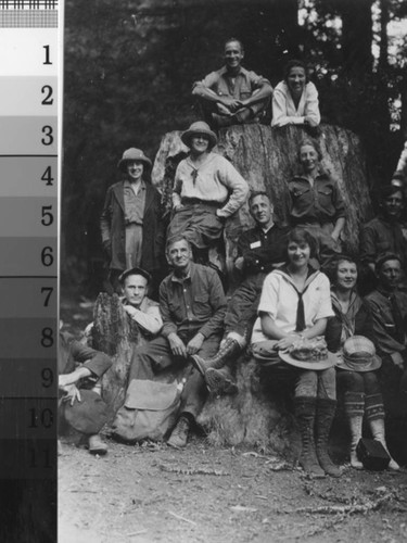 Hikers from the California Alpine Club posing around a tree trunk