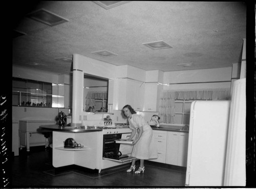 Woman doing a cooking demonstration in model kitchen for audience