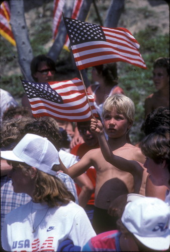 [1984 Olympics Cycling Road Race showing boys waving American flags slide]