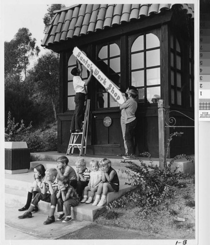 [Santa's work shop sign hanging photograph]