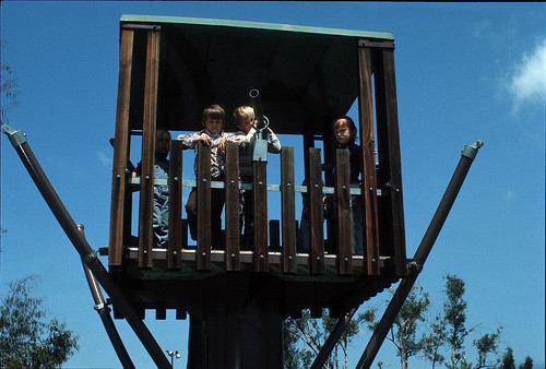 [Children on playground fort slide]