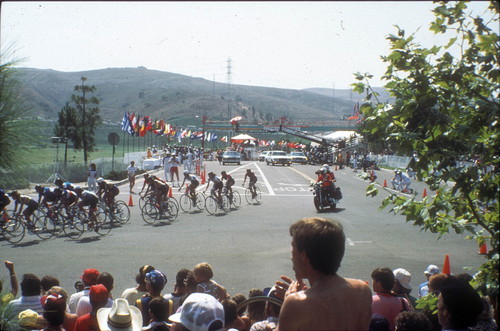 [1984 Olympics Women's Cycling Road Race with cyclists turning corner and hills in background slide]