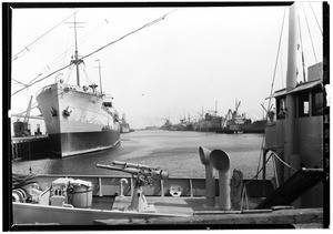 Los Angeles Harbor showing ships at outer dock across deck of Revenue Cutter showing guns, June 1, 1929