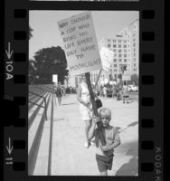 Child holding sign walks with other pickets during demonstration for Los Angeles Police officers' pay raises, 1970