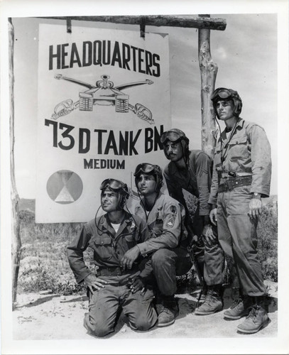 Tank crew of brothers posing with battalion headquarters sign