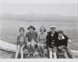 Mary McGregor, Mary Margaret Thompson and three unidentified people sitting on a log at the beach, about 1938
