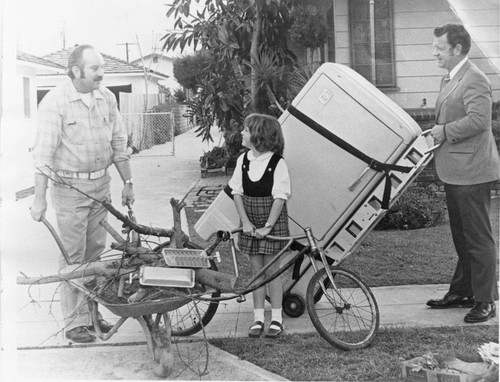 Photograph of people making room for a refrigerator