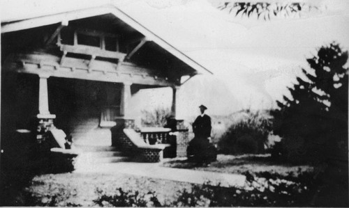 Photograph of a man standing next to a house