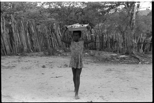 Girl walking with bowl of fish on her head, San Basilio de Palenque, 1975