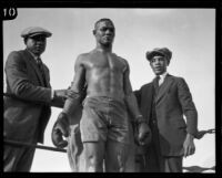 Sam Langford, boxer, in the corner of a ring between 2 staff members