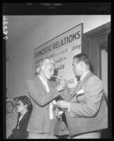 Barbara Payton has cigarette lit by Attorney Milton Golden at Courthouse during proceedings for her divorce from Franchot Tone, 1952