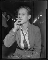 Violent thief Robert T. Fletcher sits outside courtroom smoking cigarette, Los Angeles, 1935