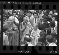 Tenzin Gyatso, Dalai Lama XIV surrounded by people during visit to Vietnamese Temple in Los Angeles, Calif., 1984