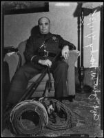 Sheriff Deputy John W. Hanby in a living room with firearms and gear, Los Angeles, 1935