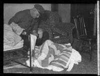 Motorcycle officer Howard J. Garner examining linens found in the apartment of William Edward Hickman murderer of Marion Parker, 1927